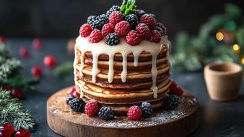 Tall stack of pancakes with white icing drizzle and fresh raspberries and blackberries on wooden board, creating cozy festive mood photo