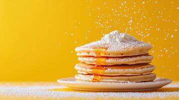 Stack of fluffy pancakes topped with powdered sugar and syrup dripping down, set against bright yellow background with falling sugar photo