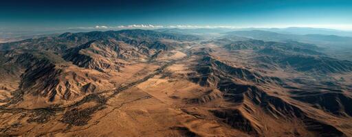Aerial view of desert landscape with mountain range and high contrast summer shadows under clear blue sky creating dramatic scene photo