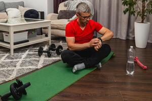 Man checking fitness tracker during home workout session photo
