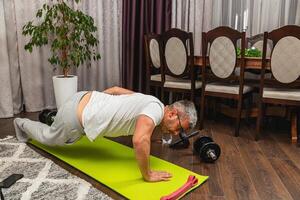 Man exercising indoors on a yoga mat in the evening photo