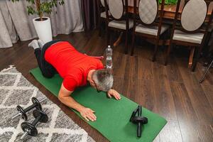 Man exercises on mat at home in the evening photo
