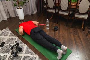 Man exercising indoors on fitness mat with dumbbells photo