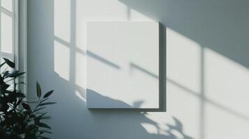Blank white vertical canvas hanging on a light gray wall with sunlight and window frame shadows. Minimalist and bright mockup space photo