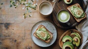 Overhead view of avocado toasts on plates, a matcha latte, and sliced avocado on wooden boards. Healthy breakfast spread on a rustic wooden table photo