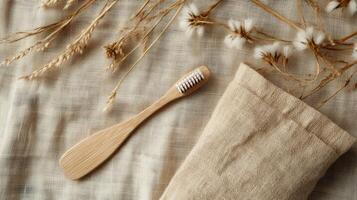 Overhead shot of a bamboo toothbrush and linen pouch with dried grasses on a textured beige cloth. Natural and sustainable oral hygiene photo