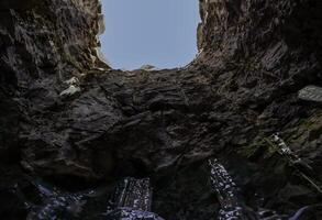 A cave with a hole in the middle and a light shining through photo