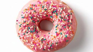A pink doughnut with sprinkles on a white surface photo
