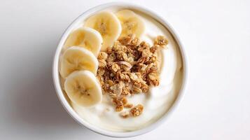 A bowl of yogurt topped with bananas and granola photo