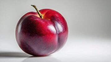 A red fruit is shown on a white surface photo