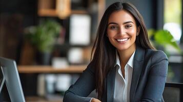 A smiling woman in a business suit sitting at a desk photo