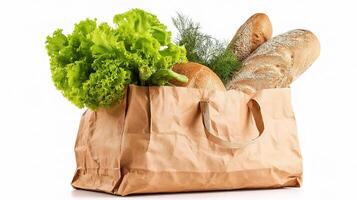 A paper bag filled with bread, lettuce and vegetables photo