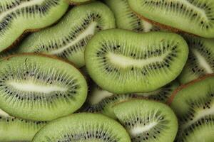 Kiwi close-up. The background is green of kiwi slices with black seeds. Natural background photo