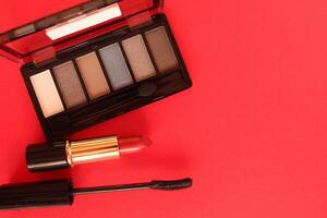 Women's Makeup. Eye Shadow Mascara Lipstick On Red Background With Place Mfor Text Top View Top View photo