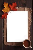 Autumn leaves and blank paper with coffee on rustic wooden table background. Space for text photo