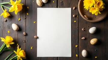 Blank paper with yellow daffodils and Easter eggs on rustic wooden table. Space for text photo