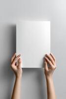 poster mockup featuring a blank white vertical sheet held up by two hands against withe background photo
