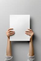 poster mockup with a blank white vertical sheet held up by two hands against withe background photo