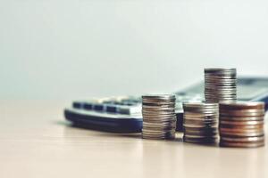 Money, coins stack, calculator and some stationery on wood table, On a bright background. Front view with copy space. Accounting and financial economic Math calculation concepts photo