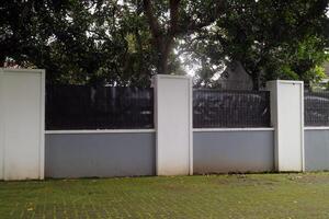 Concrete Fence with Metal Panels and Trees Behind photo