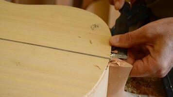 Luthier with a chisel working in a guitar video