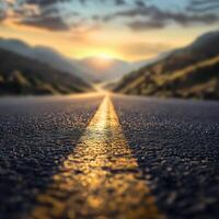 A close-up of a mountain road at sunset, with the asphalt reflecting golden light, leading into a serene valley with blurred hills and a dramatic sky, capturing the beauty of a tranquil journey. photo