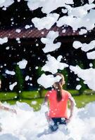 Child enjoying outdoor foam party with bubbles in summer sun, back view. photo