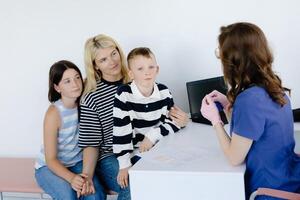 A mother with her son and daughter at a doctor's consultation in a clinic. photo