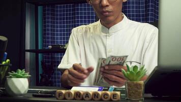 a businessman is counting some dollar bills on his desk wearing his white work shirt. business and finance concepts. video