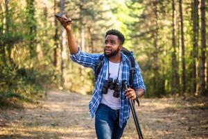 African American hiker using a mobile phone for navigation in the wilderness, trying to connect to the Internet. photo