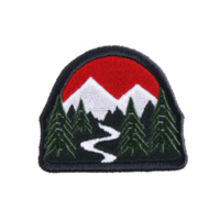A vibrant embroidered patch features red sun setting behind snow capped mountains, with winding river flowing through forest of evergreen trees, evoking sense of adventure png
