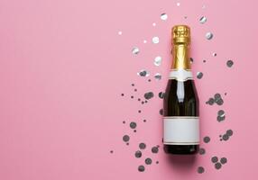 Champagne bottle with blank label on pink background surrounded by silver confetti. Celebration, anniversary, festive, party, and New Year Eve concepts. photo