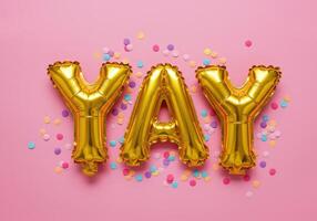 Gold foil balloons spelling YAY on pink background with colorful confetti. Celebration, party, holiday, greeting card, congratulations and positive concepts. photo
