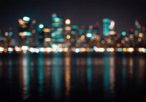 Defocused cityscape at night with blurred lights reflecting on water. Modern architecture with bokeh effect. Urban skyline with illuminated buildings. photo