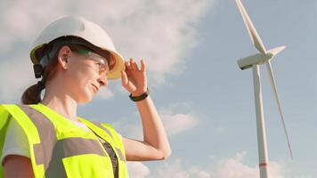 A proficient female engineer in safety gear examines a wind turbine, demonstrating commitment to renewable energy and sustainable development in her field video