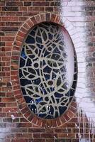 Stained glass mosaic with geometric patterns set in a weathered brick wall with paint splatters photo