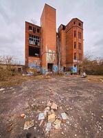 Abandoned brick factory in Germany with graffiti-covered walls, broken windows, and overgrown surroundings photo