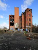 Abandoned brick building marked by graffiti and weathering under a bright, cloud-streaked sky photo