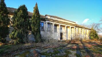 Abandoned neoclassical building in Schonebeck, Germany, with tall columns, broken windows, and overgrown vegetation photo