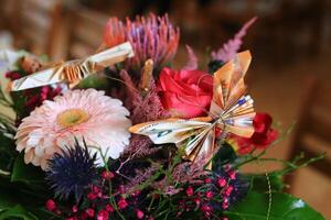 Flowers with origami - a bouquet with red and pink blooms, decorated with european money folded as butterflies photo