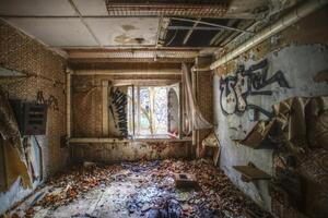 Decayed interior room with peeling wallpaper, scattered debris, graffiti, and an open window photo