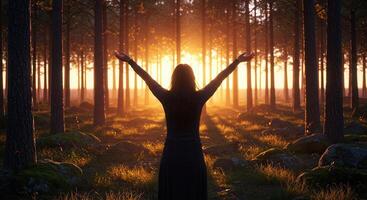 Figure with raised arms standing in a forest at sunset, illuminated by golden light, symbolizing spirituality and connection. photo