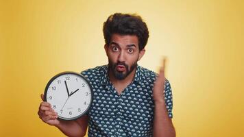 Young indian man with anxiety checking time on clock, running late to work, being in delay, deadline video