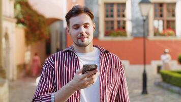 Bearded man use smartphone typing text messages browsing internet finishing work looking at camera video