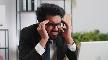 Tired indian business man suffering from headache problem tension, migraine, stress at home office video