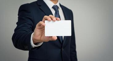 Businessman in suit holds blank white card. Professional presents empty business card for message, contact information, or marketing. Mockup template for design. photo