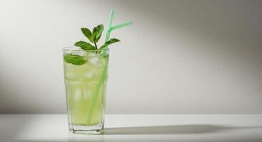 Refreshing mojito cocktail with mint leaves and ice cubes in glass with straw on white surface. Summer drink concept, studio shot, copy space. photo