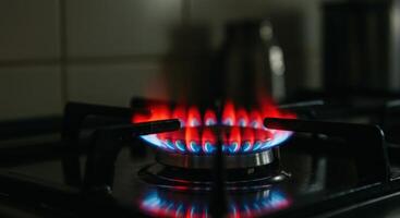 Gas stove burner with blue flame and red glow on a kitchen stove. Gas burning from a kitchen hob, dark setting. photo