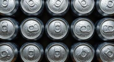 Rows of aluminum cans with water droplets, close up overhead view. Cold beverage concept, refreshment, drink industry, metal container. photo
