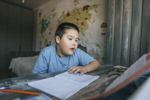asian boy reads during homework session with geography wall map, concept of home education, e-learning, tutoring services photo